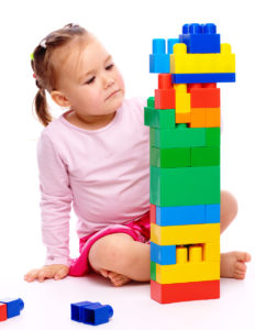 Little girl creating a tower out ofbuilding bricks