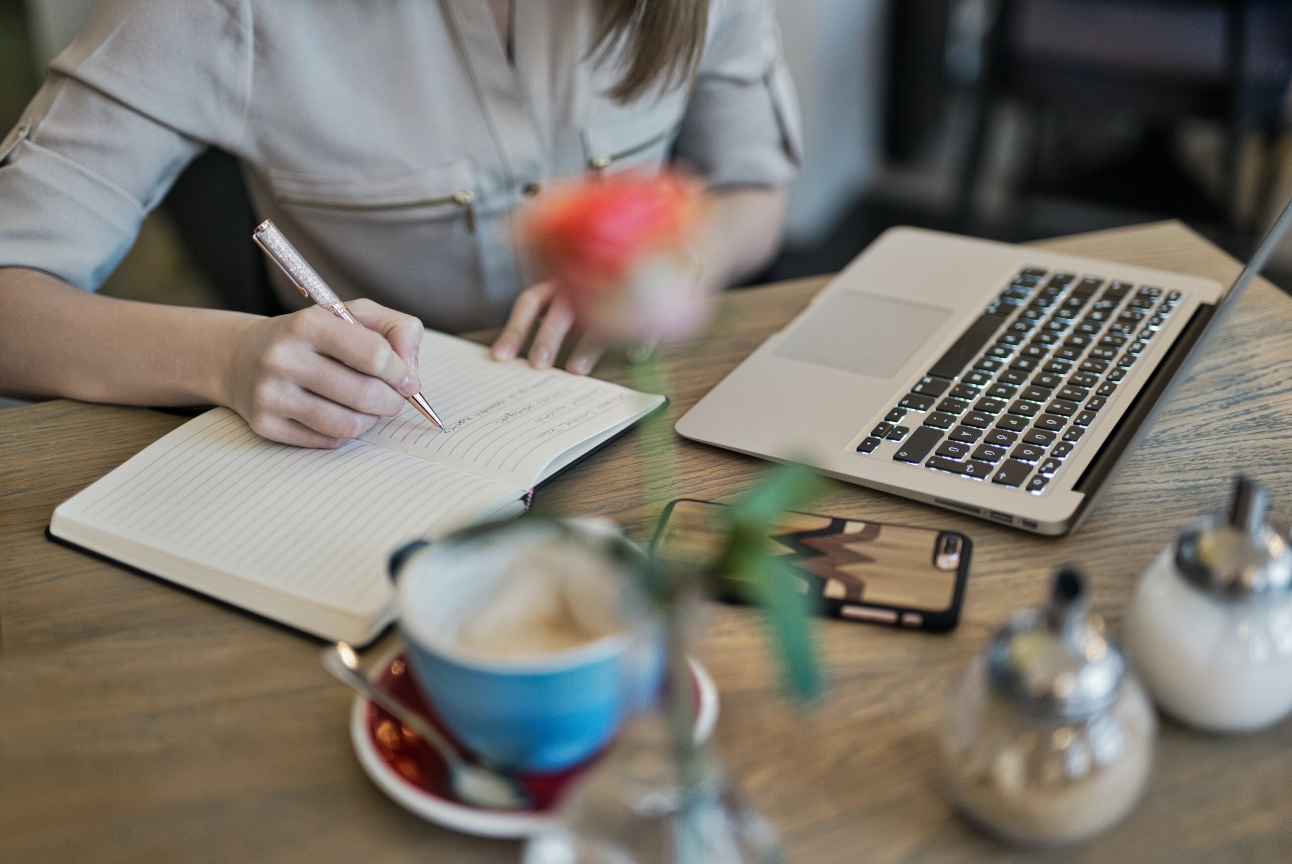 person taking notes while watching a webinar on a laptop