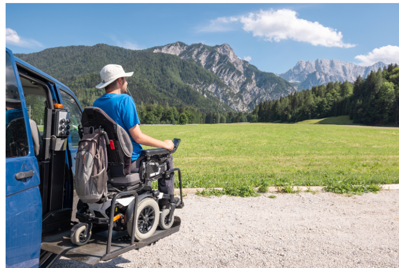 Man in a wheelchair looking at mountains in the distance. 